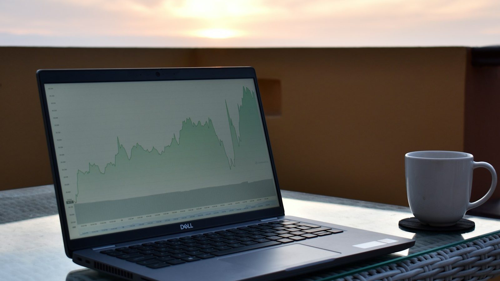 Laptop mostrando crescimento financeiro ao pôr do sol